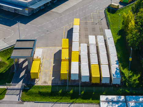 Aerial view of Logistikzentrum Allhaming featuring rows of yellow and white shipping containers parked on an asphalt lot in Allhaming Oberosterreich Austria. Aerial view of Logistikzentrum Allhaming featuring rows of yellow and white shipping containers parked on an asphalt lot in Allhaming Oberosterreich Austria.