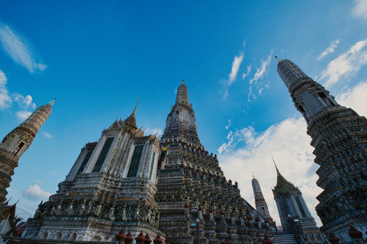 View of the ornate central prang and surrounding spires of Wat Arun temple against a clear blue sky in Bangkok Bangkok Thailand.