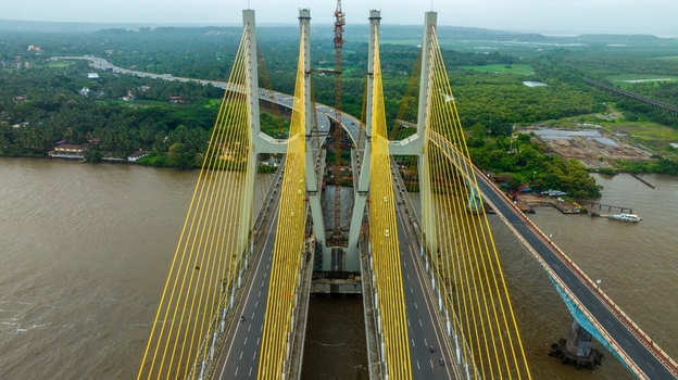 Aerial view of the Zuari Bridge spanning the river with its distinctive yellow cables and modern infrastructure in Cortalim Goa India.