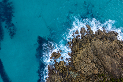 Aerial view of Conspicuous Cliff with rugged rocky coastline and turquoise ocean waves crashing against the shore in Nornalup Western Australia Australia. Aerial view of Conspicuous Cliff with rugged rocky coastline and turquoise ocean waves crashing against the shore in Nornalup Western Australia Australia.