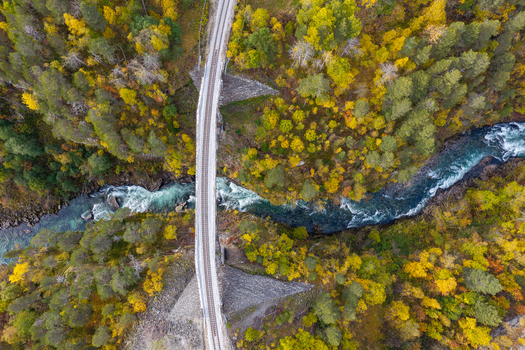 Aerial view of Kylling Bridge spanning a rushing river through a dense forest with vibrant autumn foliage in Verma More og Romsdal Norway. Aerial view of Kylling Bridge spanning a rushing river through a dense forest with vibrant autumn foliage in Verma More og Romsdal Norway.