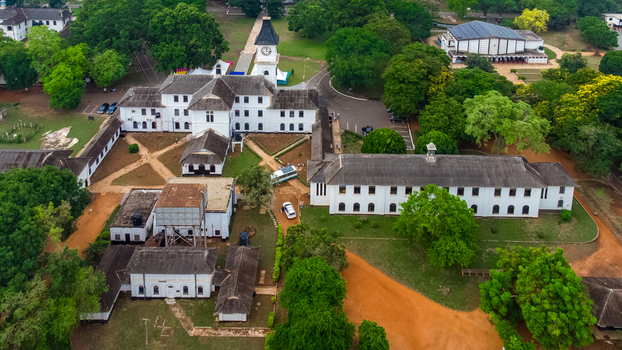 Aerial view of Achimota School featuring historic white colonial style buildings a prominent clock tower lush green trees and red dirt paths in Achimota Greater Accra Region Ghana. Aerial view of Achimota School featuring historic white colonial style buildings a prominent clock tower lush green trees and red dirt paths in Achimota Greater Accra Region Ghana.