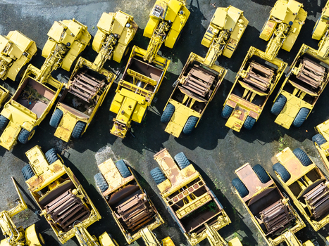 Aerial view of a fleet of yellow industrial earthmoving scrapers parked in an organized lot in Woodburn Oregon United States. Aerial view of a fleet of yellow industrial earthmoving scrapers parked in an organized lot in Woodburn Oregon United States.