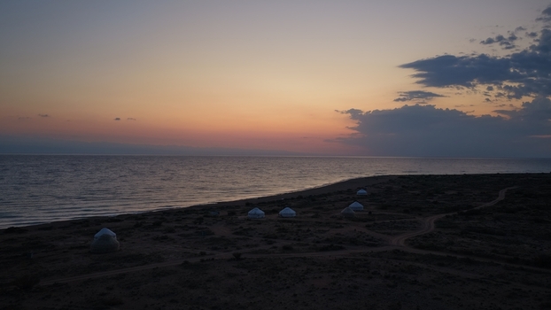 Aerial view of yurts scattered along the shore of Issyk Kul lake under a vibrant sunset sky in Issyk Kul Region Kyrgyzstan. Aerial view of yurts scattered along the shore of Issyk Kul lake under a vibrant sunset sky in Issyk Kul Region Kyrgyzstan.