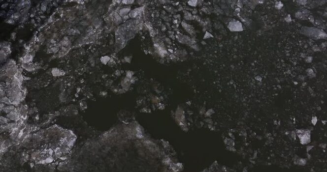 Aerial view of broken ice floes on dark river water United States.