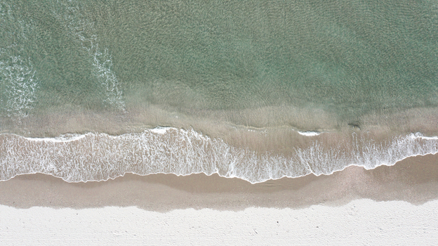 Aerial view of the white sand beach and clear turquoise water at Omaha Beach Omaha Auckland New Zealand.