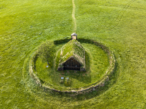 Aerial view of a traditional turf roofed church nestled within a circular stone enclosure surrounded by lush green fields in Iceland. Aerial view of a traditional turf roofed church nestled within a circular stone enclosure surrounded by lush green fields in Iceland.