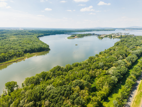 Aerial view of the wide river winding through dense green forests and a small harbor under a clear blue sky in Bratislava Bratislava Region Slovakia. Aerial view of the wide river winding through dense green forests and a small harbor under a clear blue sky in Bratislava Bratislava Region Slovakia.