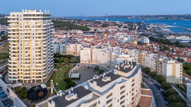 Aerial view of a modern residential high rise building and surrounding urban landscape with red tiled rooftops green spaces and the Tagus River in Lisbon Lisbon Portugal.