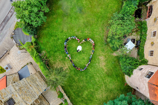 Wiesenthau Germany 02 May 2026 Aerial view of Schloss Wiesenthau with wedding guests forming a heart shape around a bride and groom on a green lawn. Wiesenthau Germany 02 May 2026 Aerial view of Schloss Wiesenthau with wedding guests forming a heart shape around a bride and groom on a green lawn.