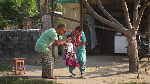 View of a family feeding a child on a swing in Dhangadhi Nepal. View of a family feeding a child on a swing in Dhangadhi Nepal.