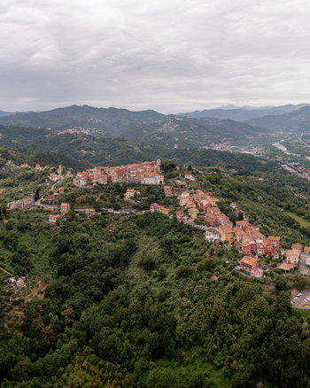 Aerial view of the historic hilltop town of Vezzano Ligure with its dense cluster of terracotta rooftops nestled among lush green hills and rolling mountains in Vezzano Ligure Liguria Italy.