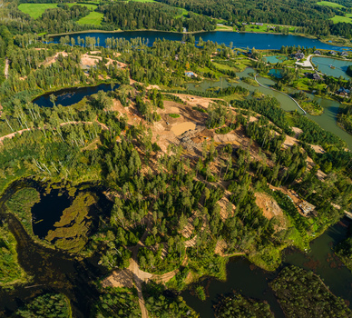 Aerial view of a lush landscape featuring interconnected lakes dense pine forests and an area of cleared land with exposed earth in Latvia. Aerial view of a lush landscape featuring interconnected lakes dense pine forests and an area of cleared land with exposed earth in Latvia.
