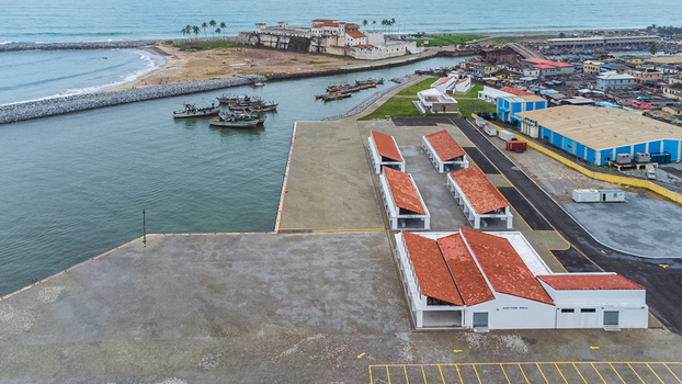 Aerial view of Elmina Castle overlooking the harbor with fishing boats and the modern auction hall in Elmina Central Region Ghana. Aerial view of Elmina Castle overlooking the harbor with fishing boats and the modern auction hall in Elmina Central Region Ghana.