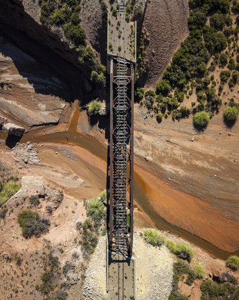 Aerial view of a historic railway bridge spanning a dry riverbed in an arid desert landscape with sparse vegetation and rocky terrain in Argentina. Aerial view of a historic railway bridge spanning a dry riverbed in an arid desert landscape with sparse vegetation and rocky terrain in Argentina.
