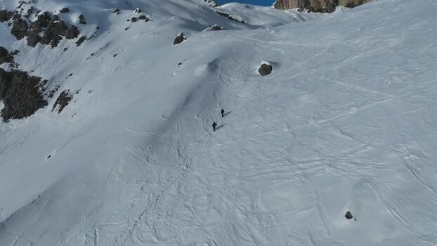 Aerial view of hikers on snowy mountain slopes Italy.