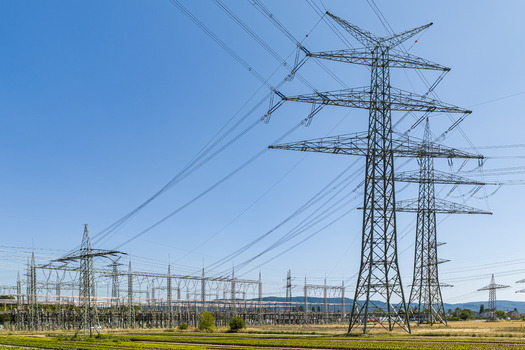 Aerial view of the Amprion Umspannwerk electrical substation featuring large high voltage transmission towers and power lines set against a clear blue sky in Pfungstadt Hessen Germany.