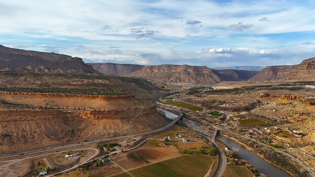 Aerial view of the winding river snaking through the rugged canyon painting the landscape with earthy tones under a vast sky Palisade Colorado USA. Aerial view of the winding river snaking through the rugged canyon painting the landscape with earthy tones under a vast sky Palisade Colorado USA.