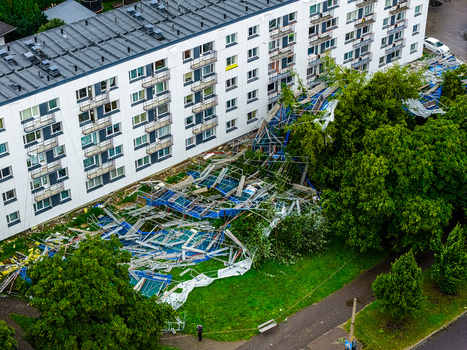 Riga Latvia 23 August 2026 Aerial view of storm damage showing collapsed scaffolding and debris scattered across the lawn next to a residential apartment building.