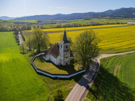 Aerial view of the historic All Saints Church surrounded by a stone wall and vibrant yellow rapeseed fields in Ludrova Zilina Region Slovakia. Aerial view of the historic All Saints Church surrounded by a stone wall and vibrant yellow rapeseed fields in Ludrova Zilina Region Slovakia.
