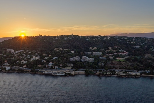 Aerial view of the coastal town of Antibes at sunset with residential buildings nestled on the hillside overlooking the Mediterranean Sea in Antibes Provence Alpes Cote d Azur France. Aerial view of the coastal town of Antibes at sunset with residential buildings nestled on the hillside overlooking the Mediterranean Sea in Antibes Provence Alpes Cote d Azur France.
