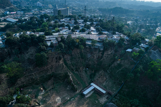 Chittagong Bangladesh 10 March 2022 Aerial view of a hillside settlement in a landslide prone zone featuring houses built on steep slopes surrounded by dense vegetation and urban infrastructure.