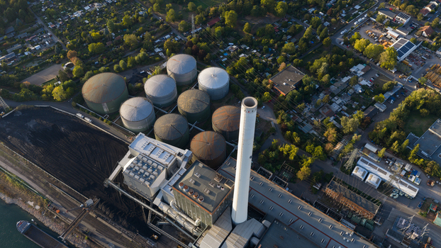 Aerial view of the large power plant in Mannheim AG with its tall chimney and industrial storage tanks near greenery and urban infrastructure in Mannheim Baden Wurttemberg Germany.