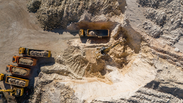 Aerial view of the Besenovo quarry with heavy machinery including an excavator loading soil into dump trucks surrounded by excavated earth and rocky terrain in Besenovo Vojvodina Serbia. Aerial view of the Besenovo quarry with heavy machinery including an excavator loading soil into dump trucks surrounded by excavated earth and rocky terrain in Besenovo Vojvodina Serbia.