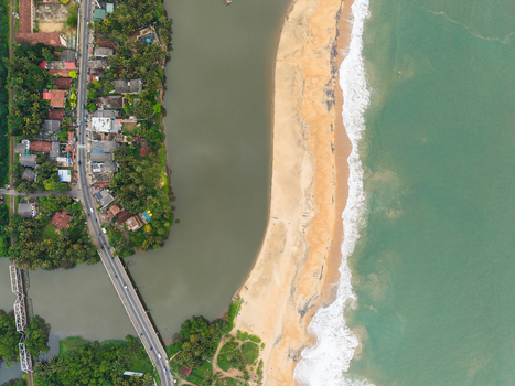 Aerial view of a sandy beach and turquoise ocean waves meeting a river mouth with lush palm trees and a coastal road Galle Southern Province Sri Lanka. Aerial view of a sandy beach and turquoise ocean waves meeting a river mouth with lush palm trees and a coastal road Galle Southern Province Sri Lanka.