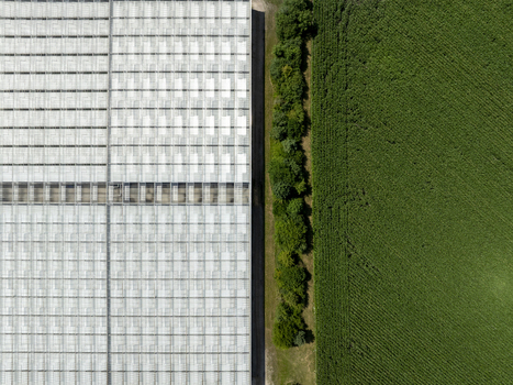 Aerial view of a large greenhouse structure adjacent to a green agricultural field in Aschheim Bavaria Germany.