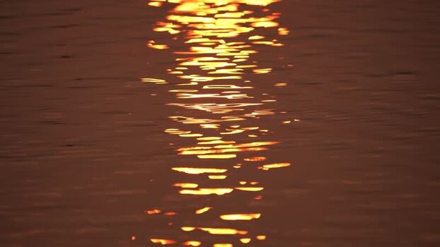 View of golden sunlight reflecting on water ripples Bangladesh.
