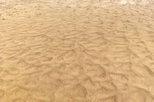 Aerial view of the vast desert landscape featuring intricate sand ripple patterns and golden dunes in Senek Mangystau Region Kazakhstan.