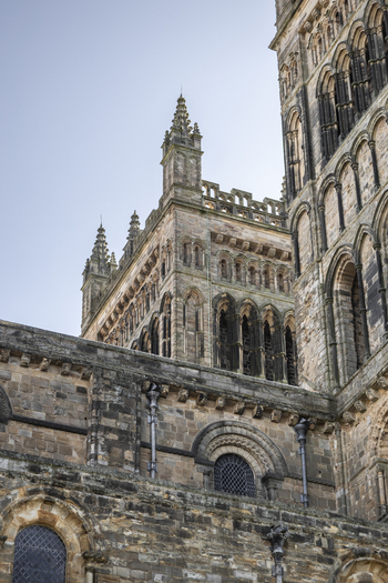 View of the historic stone architecture of Durham Cathedral featuring intricate Romanesque arches weathered masonry and towering spires in Durham England United Kingdom. View of the historic stone architecture of Durham Cathedral featuring intricate Romanesque arches weathered masonry and towering spires in Durham England United Kingdom.