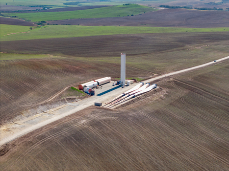 Aerial view of a wind turbine construction site with a white tower and large blades lying on the ground in a rural landscape Swellendam Western Cape South Africa. Aerial view of a wind turbine construction site with a white tower and large blades lying on the ground in a rural landscape Swellendam Western Cape South Africa.
