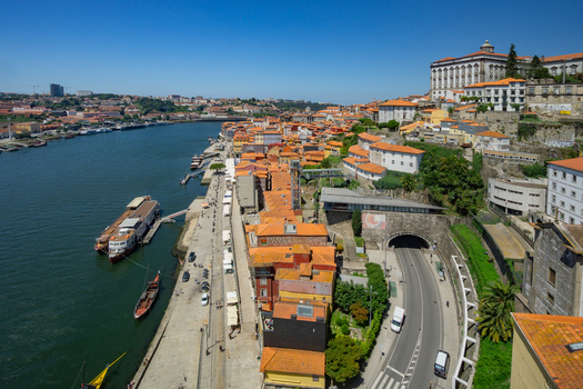 Aerial view of terracotta rooftops cascading down to the Douro River where boats glide under the Dom Luís I Bridge Porto Porto District Portugal. Aerial view of terracotta rooftops cascading down to the Douro River where boats glide under the Dom Luís I Bridge Porto Porto District Portugal.
