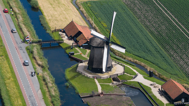 Aerial view of the historic Schermerhorn windmill situated beside a tranquil canal adjacent to a road and lush agricultural fields in Schermerhorn North Holland Netherlands. Aerial view of the historic Schermerhorn windmill situated beside a tranquil canal adjacent to a road and lush agricultural fields in Schermerhorn North Holland Netherlands.