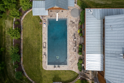 Harrisonburg Virginia United States 09 August 2021 Aerial view of a rectangular swimming pool with a diving board stone patio and lawn next to a house. Harrisonburg Virginia United States 09 August 2021 Aerial view of a rectangular swimming pool with a diving board stone patio and lawn next to a house.