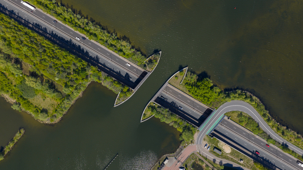Aerial view of the Aquaduct Veluwemeer with cars driving on the road passing under the water bridge surrounded by lush green trees Harderwijk Gelderland Netherlands. Aerial view of the Aquaduct Veluwemeer with cars driving on the road passing under the water bridge surrounded by lush green trees Harderwijk Gelderland Netherlands.