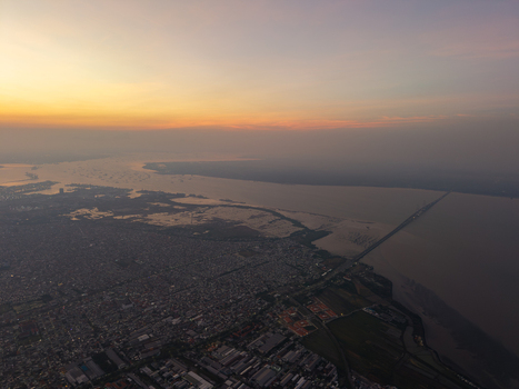 Aerial view of the Suramadu Bridge spanning the Madura Strait at sunset with urban sprawl in Surabaya East Java Indonesia.