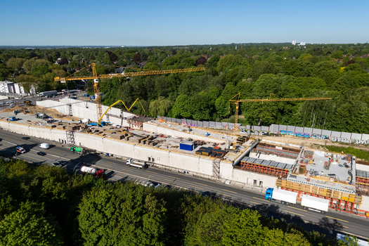 Aerial view of the construction site in Bahrenfeld with yellow cranes concrete walls and trucks surrounded by green trees in Hamburg Hamburg Germany.