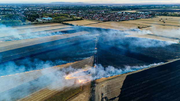 Aerial view of a controlled agricultural field fire with smoke rising over harvested farmland near the town of Sremska Mitrovica Vojvodina Serbia. Aerial view of a controlled agricultural field fire with smoke rising over harvested farmland near the town of Sremska Mitrovica Vojvodina Serbia.