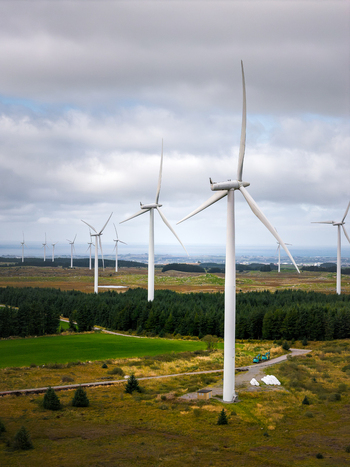 Aerial view of the Hog Jaeren wind farm featuring tall white wind turbines set against a rural landscape with green fields forests and a cloudy sky in Ha Municipality Rogaland Norway. Aerial view of the Hog Jaeren wind farm featuring tall white wind turbines set against a rural landscape with green fields forests and a cloudy sky in Ha Municipality Rogaland Norway.