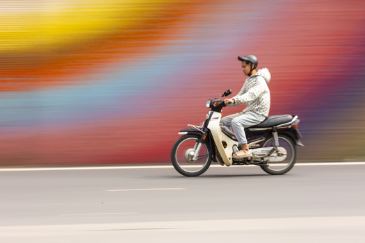 Hanoi Vietnam 11 November 2025 View of a man riding a motorbike on a road with a colorful motion blurred background.