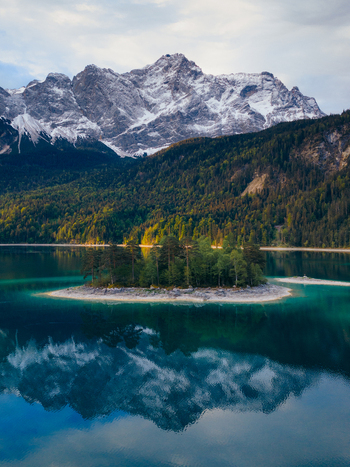 Aerial view of the turquoise Eibsee lake with a small island and the reflection of the snow capped Zugspitze mountain in Grainau Bavaria Germany. Aerial view of the turquoise Eibsee lake with a small island and the reflection of the snow capped Zugspitze mountain in Grainau Bavaria Germany.