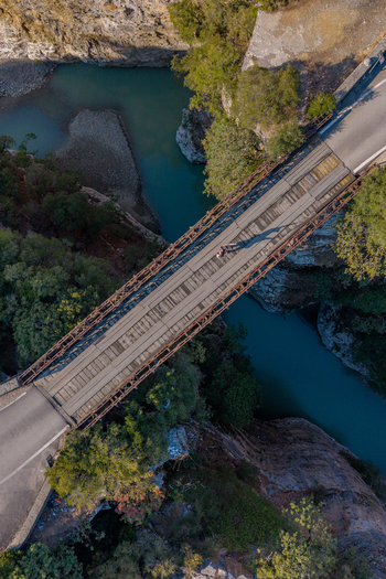 Aerial view of the bridge spanning the Osumi Canyon with turquoise river waters lush green trees and rocky cliffs in Dhores Berat County Albania.