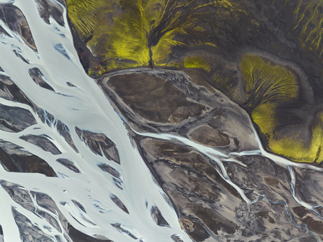 Aerial view of glacial rivers carving through the Icelandic landscape a tapestry of white streams against dark earth and vibrant green moss Highlands Iceland.