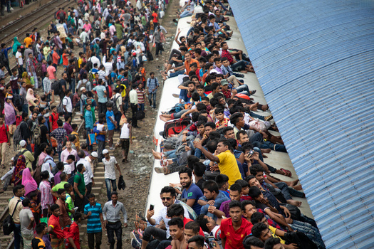 Dhaka Bangladesh 15 June 2018 View of a massive crowd of passengers sitting on the roof of a train and standing on the tracks at Airport Railway Station during a busy travel period. Dhaka Bangladesh 15 June 2018 View of a massive crowd of passengers sitting on the roof of a train and standing on the tracks at Airport Railway Station during a busy travel period.