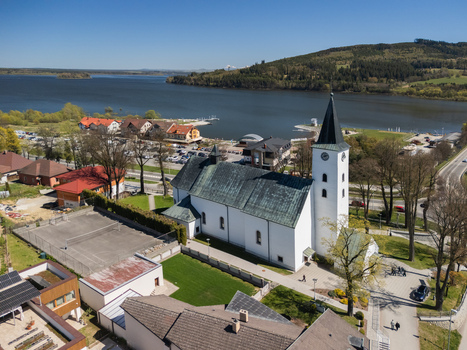 Aerial view of the Roman Catholic Church of Saints Simon and Jude with its tall steeple overlooking the Orava Reservoir and green hills in Namestovo Zilina Region Slovakia. Aerial view of the Roman Catholic Church of Saints Simon and Jude with its tall steeple overlooking the Orava Reservoir and green hills in Namestovo Zilina Region Slovakia.