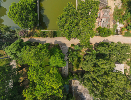 Lahore Pakistan 08 September 2026 Aerial view of a lush park surrounding a government office featuring dense trees a small pond and paved pathways in bright daylight.