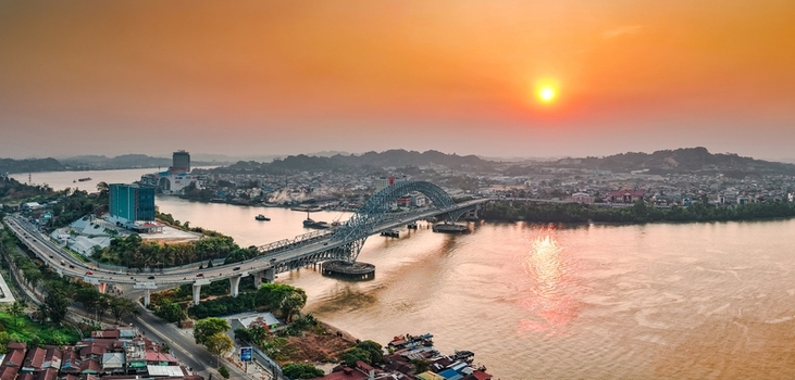 Aerial view of Jembatan Mahakam I spanning the Mahakam River at sunset with urban surroundings and lush hills in Kecamatan Samarinda Seberang Kalimantan Timur Indonesia. Aerial view of Jembatan Mahakam I spanning the Mahakam River at sunset with urban surroundings and lush hills in Kecamatan Samarinda Seberang Kalimantan Timur Indonesia.